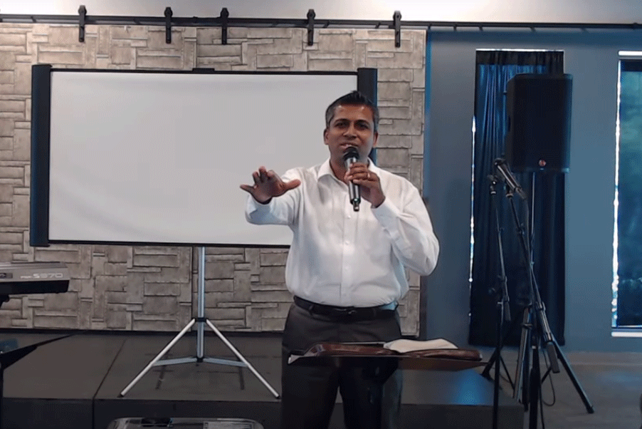 A man giving a speech in front of a screen.